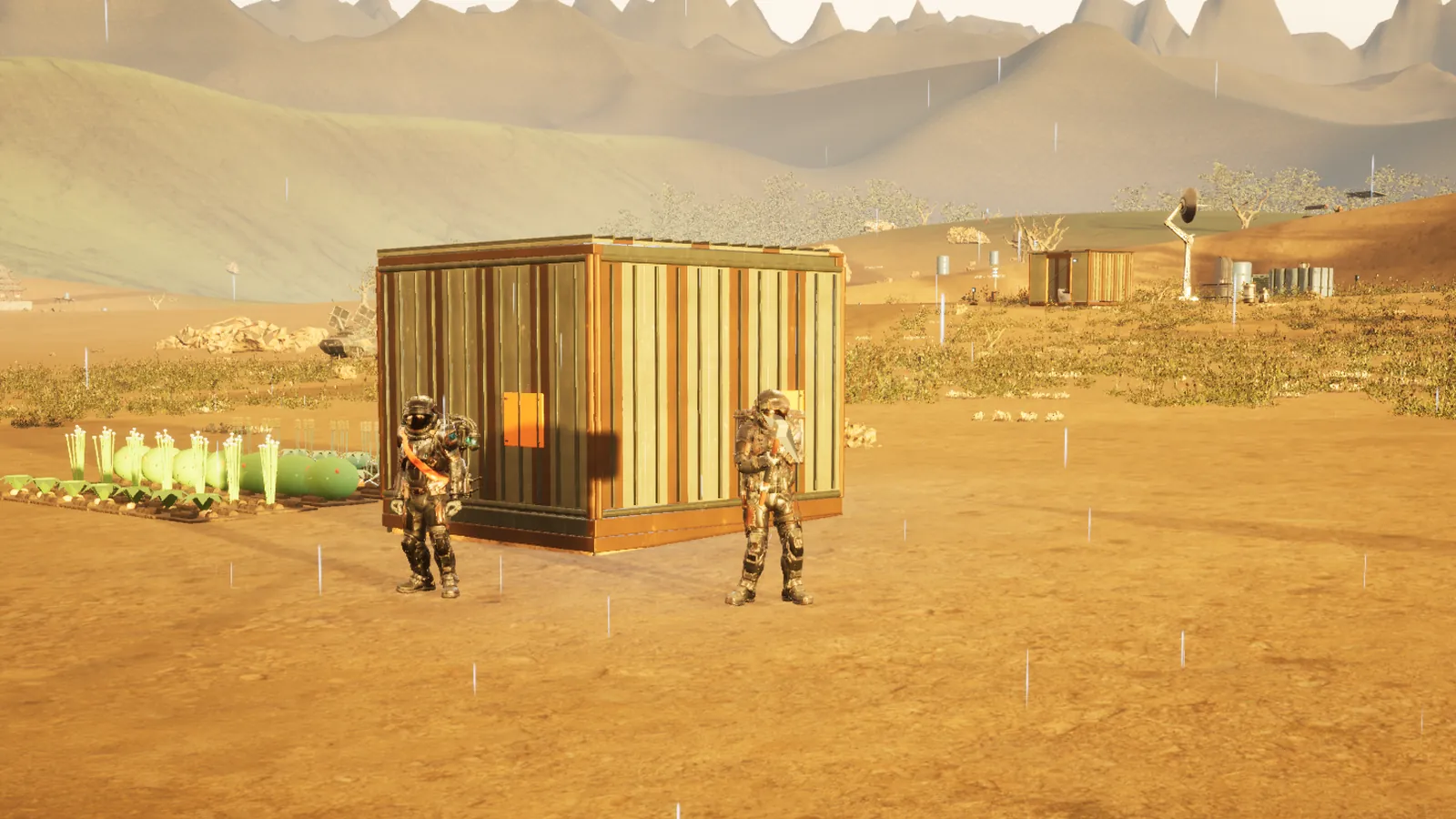 Two explorers stand by their shelter and crops in low evening light